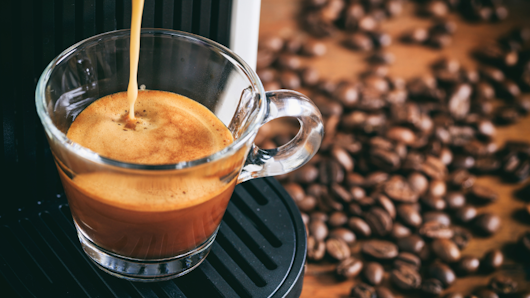 Shot of espresso with coffee beans in background.