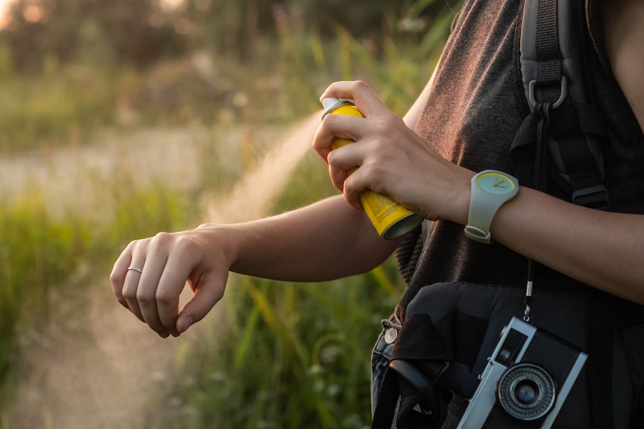 Close-up of young tourist applying mosquito spray on arms.