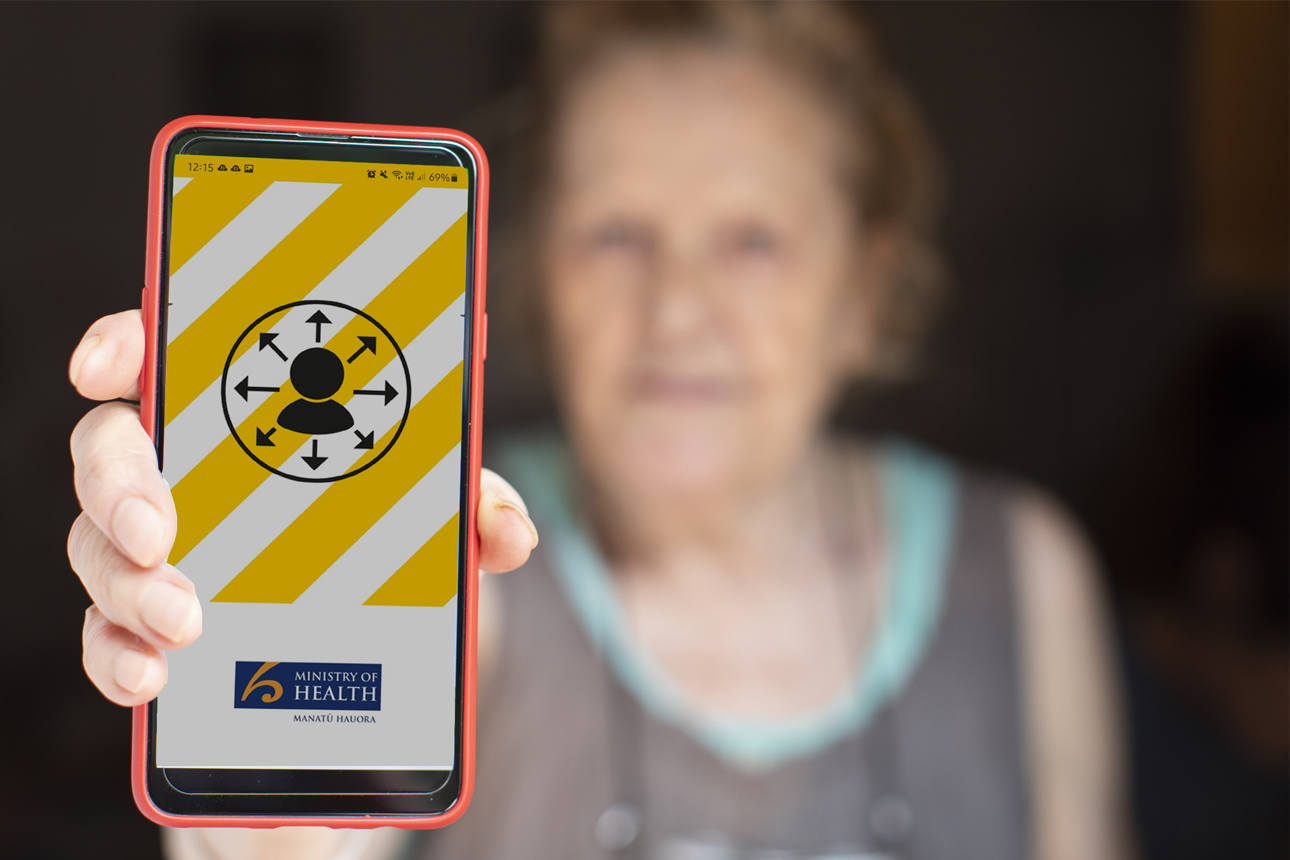Elderly woman showing a COVID-19 tracing app displaying on mobile phone.