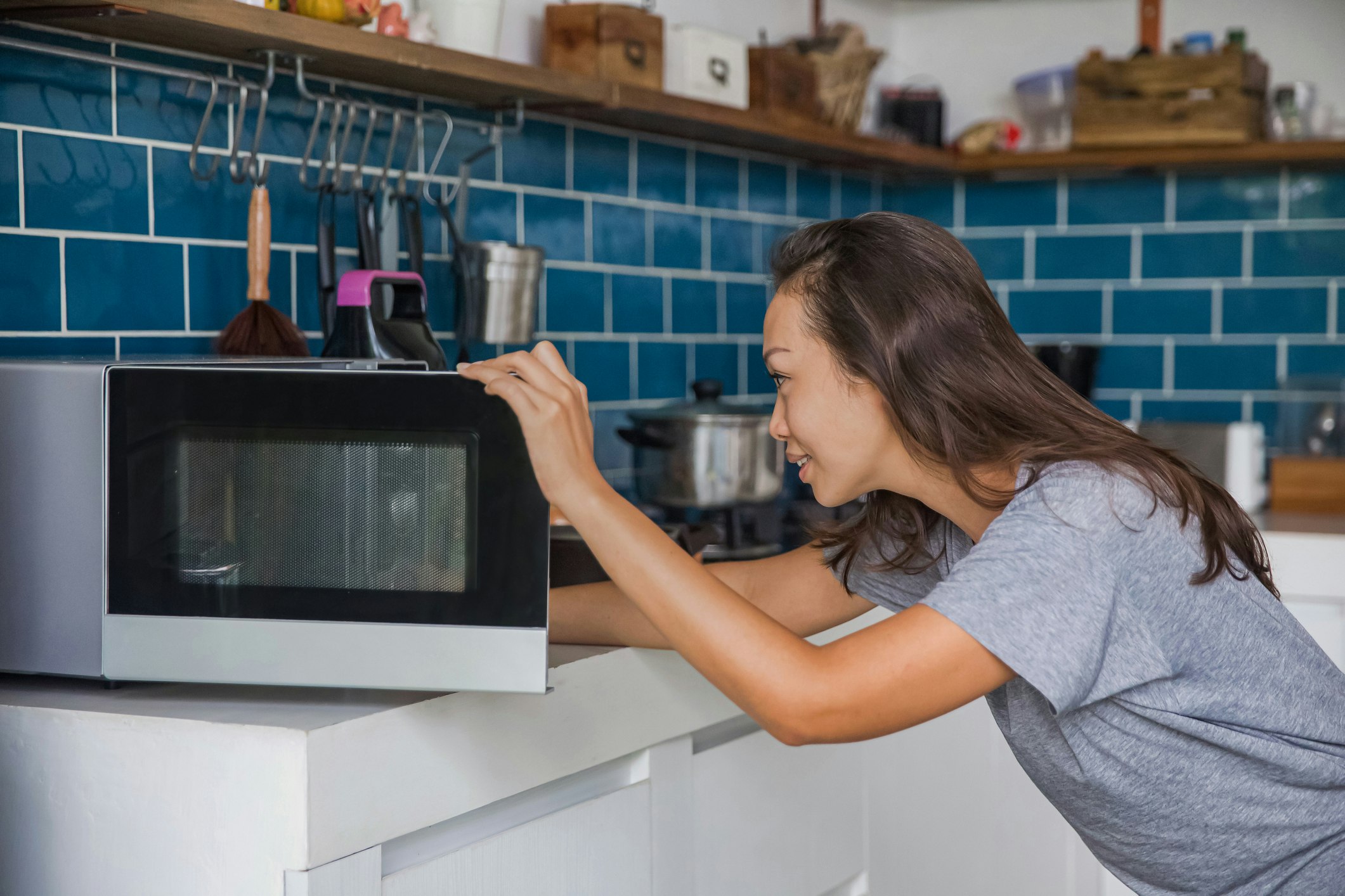 Side shot of woman opening her microwave.