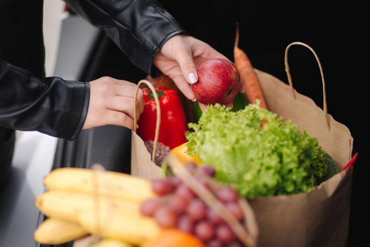Person putting fruits into paper bag.