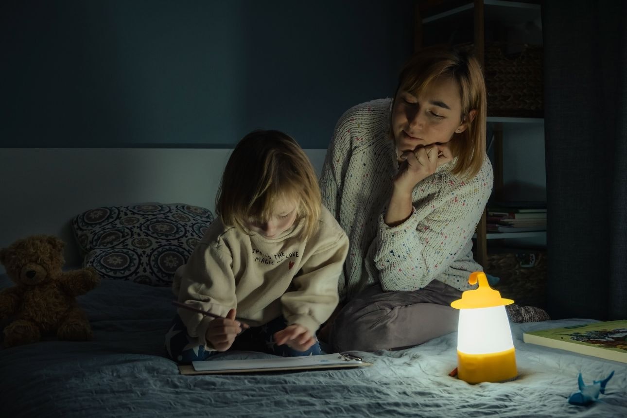 Image of a mother and daughter with a lantern in a dark room.