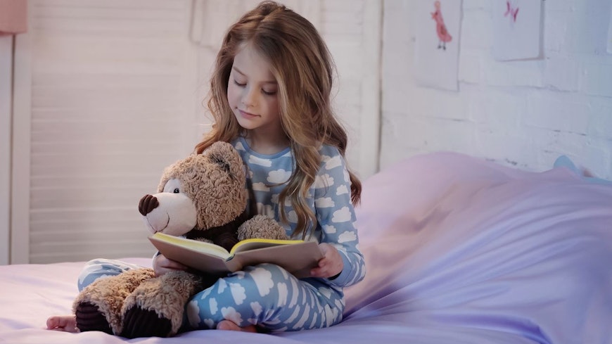 Image of a kid reading a book in bed