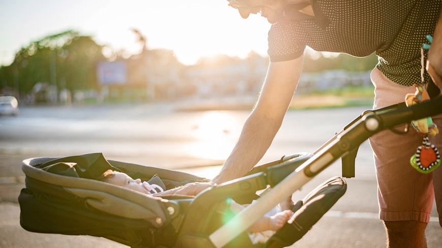 Father and baby in stroller walking on sunset.