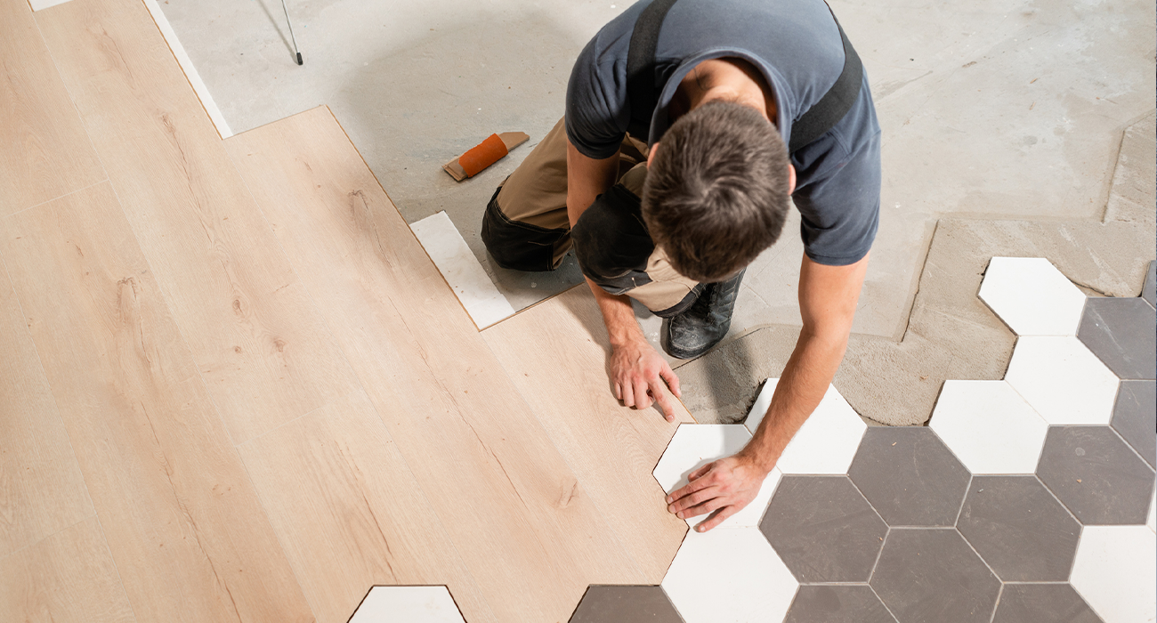 Male worker installing new wooden laminate flooring.