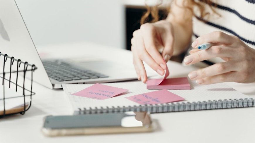 Image of a person writing on a sticky note
