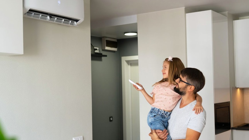 Father with daughter turning on air conditioner