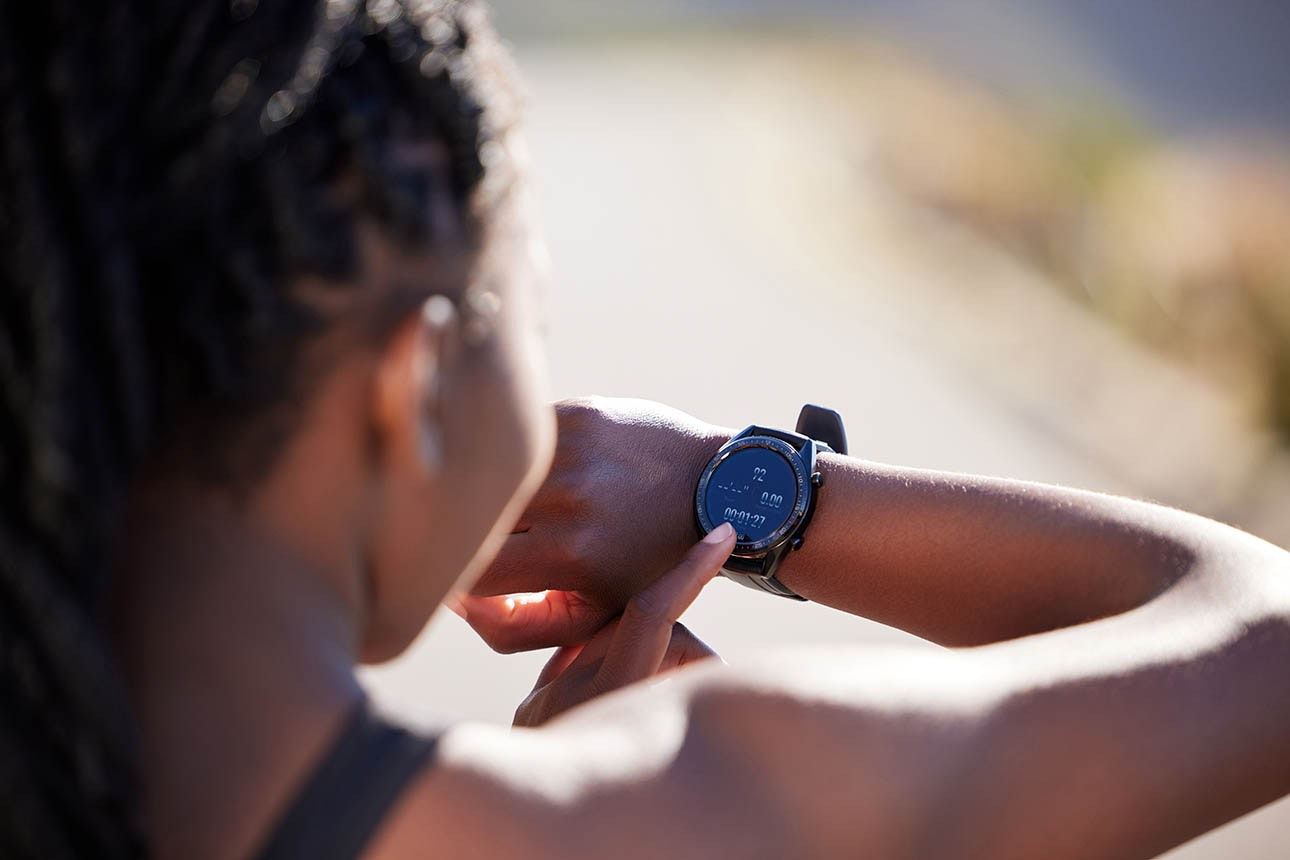 Black woman checking fitness tracker on her wrist.