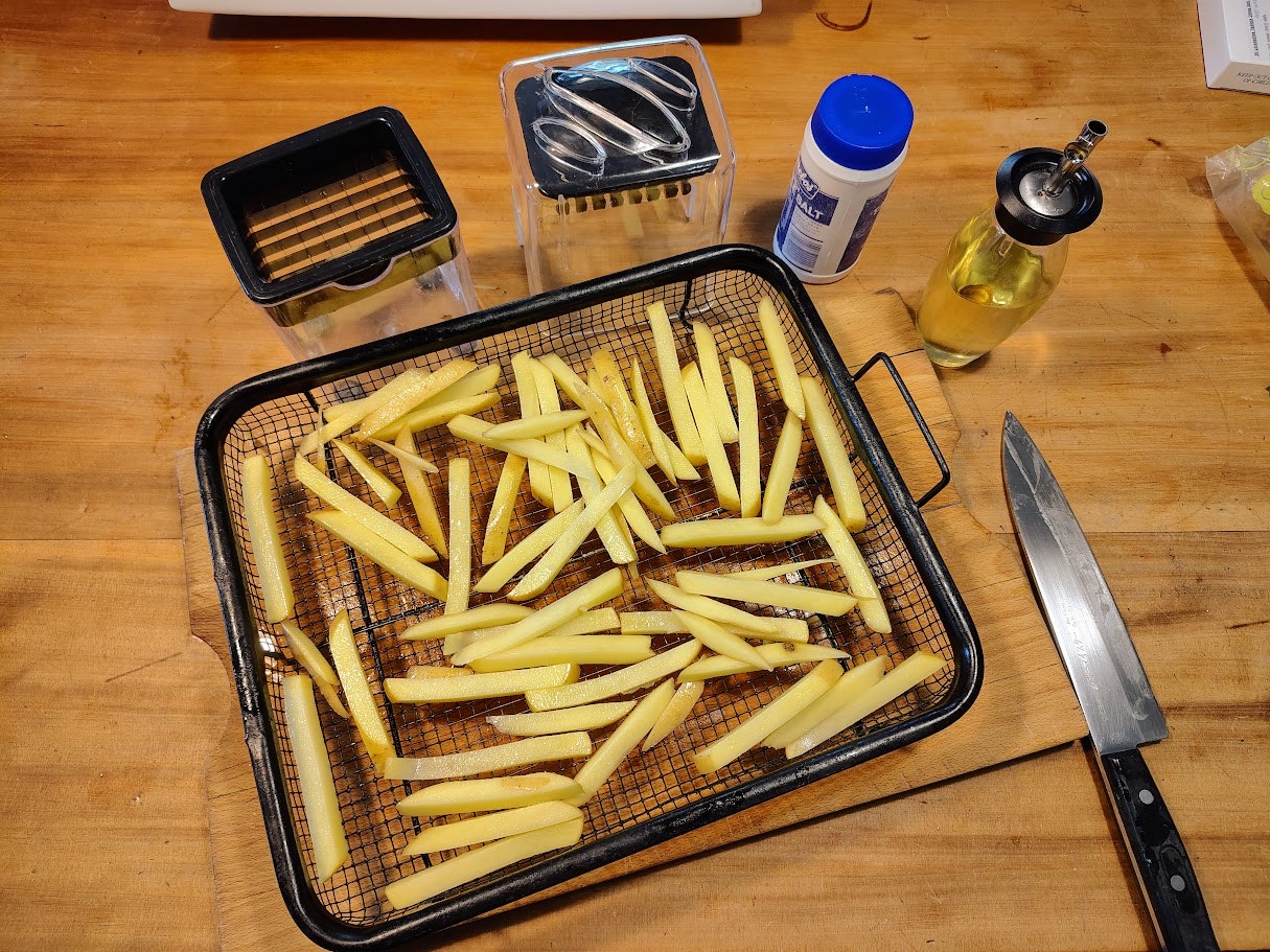Sliced potato chips in an air fryer basket.